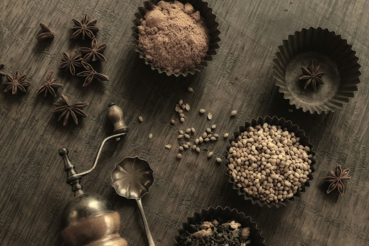 Assorted spices and dried herbs arranged on a rustic wooden table.