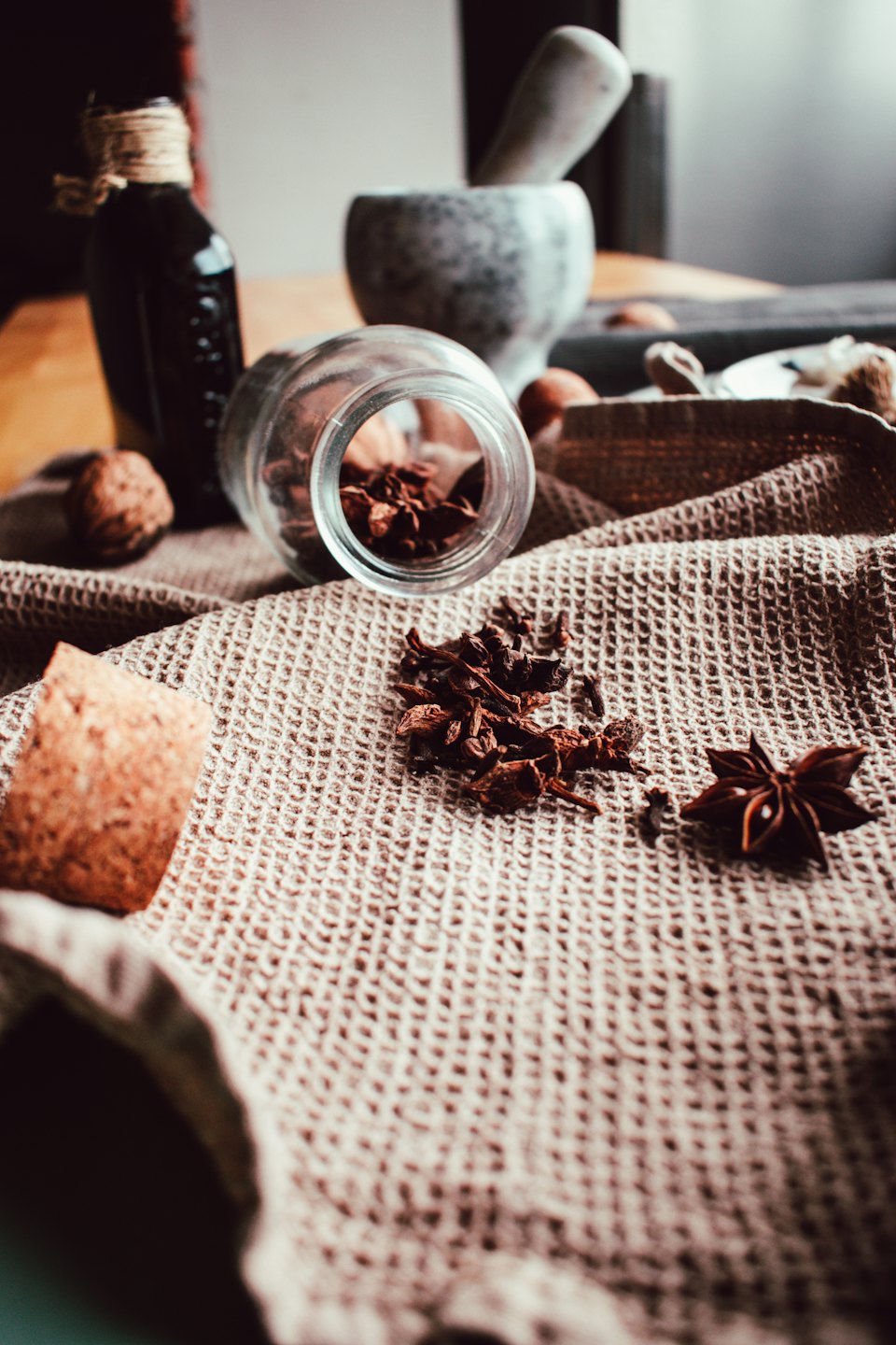 Spices and walnuts arranged with a mortar on a towel.