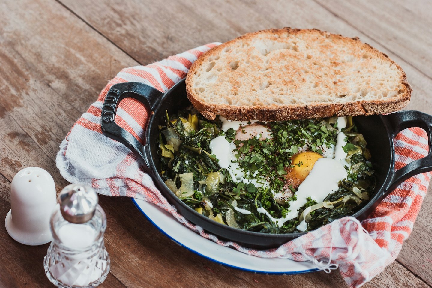 Cast iron skillet with vegetable and egg dish, parsley, and sourdough toast.