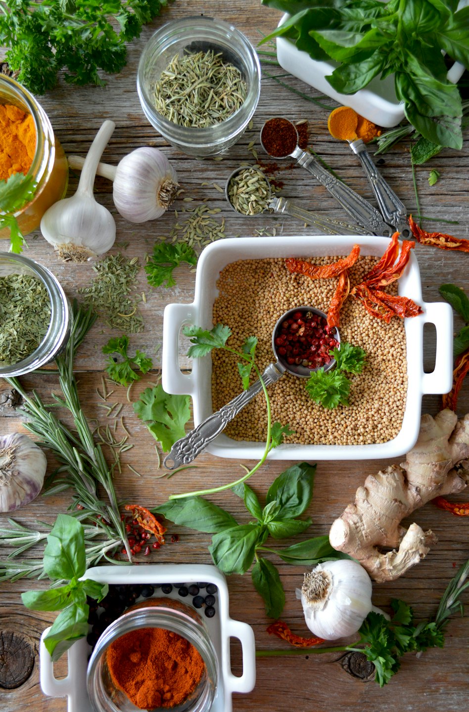 Assorted fresh and dried herbs and spices arranged on wood.